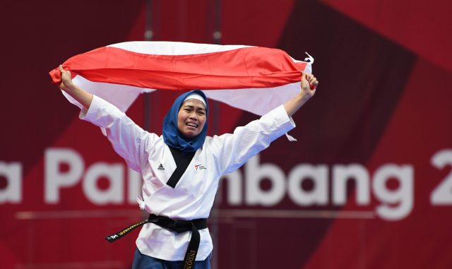 Atlet Taekwondo putri Indonesia Rosmaniar Defia berlari membawa bendera merah putih usai menang melawan Taekwondoin putri Iran Marjan Salahshouri pada partai final poomsae individu pada Asian Games 2018 di Jakarta Convention Center, Defia menang dan memper